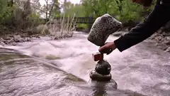 hand balancing rock on cairn in river