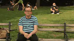 Man on bench waves at guy in background