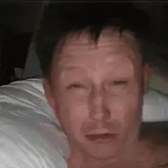 Man lying in bed blinking