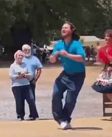 Man in blue shirt dancing energetically outdoors