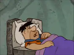 Fred Flintstone sleeping in bed