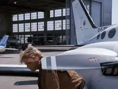 Maverick stands up and smiles by jet