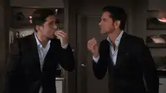 Two men in suits eating and laughing