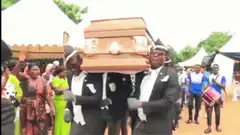 men dancing with coffin at funeral