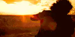 person throwing hat at sunset