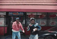 Two men dancing outside a pizza place