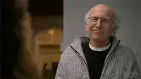 Larry David laughing and waving hands