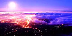 Volcano erupting above clouds at sunset