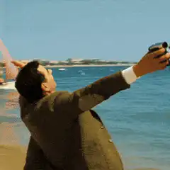 Man in suit taking selfie on beach