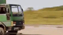Green truck drifting and hitting a pole