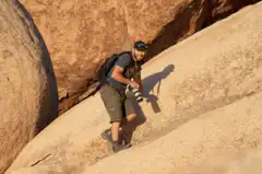 Man hiking up a steep rock with camera