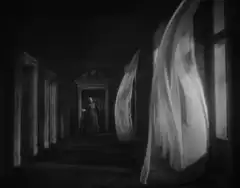 Woman in hallway with blowing curtains