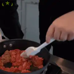 Hand stirring raw ground meat in a pan