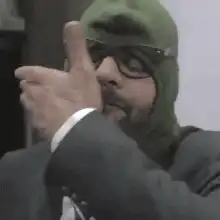 Man in green ski mask gives thumbs up then facepalms
