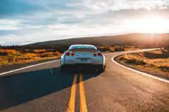 white sports car on road at sunset