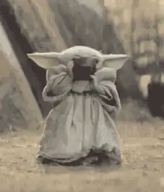 Baby Yoda drinking from a cup