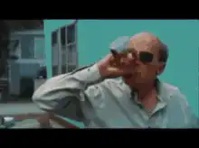 Bald man drinks from a bottle and falls into a car