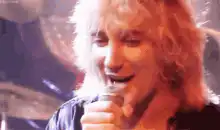 Brian May singing and covering his mouth