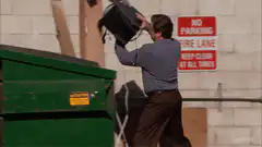 man throws backpack into dumpster