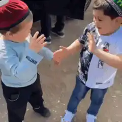 Two young boys in kippahs hug