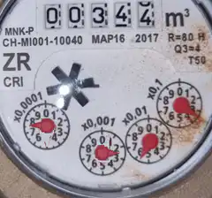 Close-up of a water meter with spinning dials