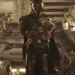 The Mandalorian holding Grogu