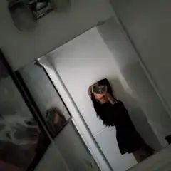 Girl in black dress taking mirror selfie