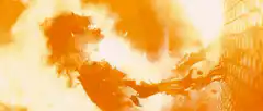 Orange explosion shattering a chain link fence