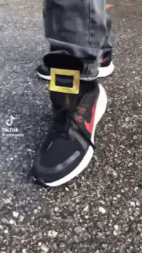 person wearing giant gold buckles on sneakers