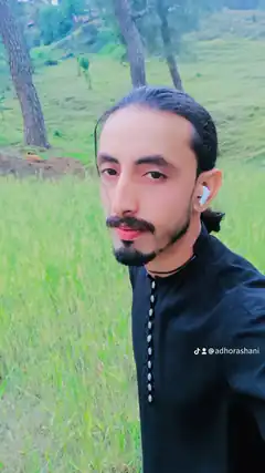 Man with mustache and earbud in green field