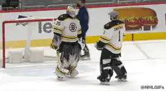 Two hockey goalies celebrate and hug