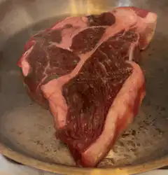 Raw steak sizzling in a pan