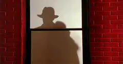 Man in hat smashes through window