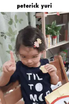 Toddler eating cracker and wagging finger