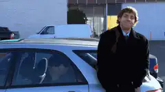 John Green smirking by a car