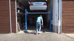 Man in garage with car on lift