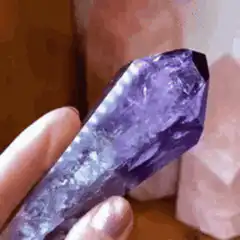 Hand holding purple amethyst crystal