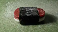 Hand wrapping nori around tuna sushi