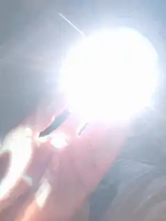 Hand holding a bright light bulb