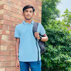 Young man with backpack by brick wall