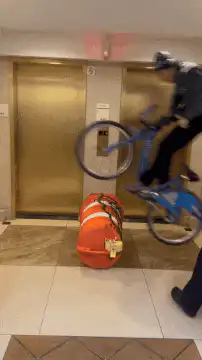 cyclist jumps over duffel bag in elevator lobby