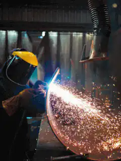 Worker welding metal sheet with sparks