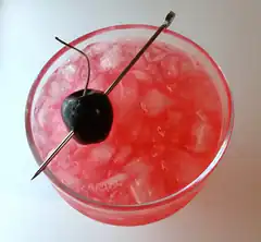 Top view of a red cocktail with ice and cherry