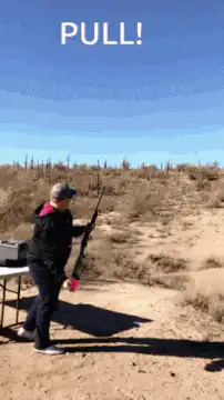 Woman shooting clay pigeon in desert