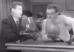 Two men blow up balloons that pop