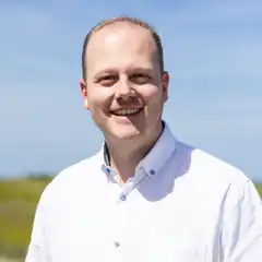 Man in white shirt smiling outdoors