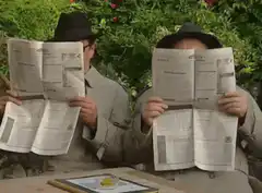 Two men reading newspapers in the garden