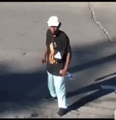 Man in white hat walking on pavement