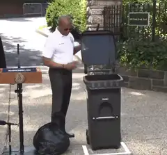 Man throws trash bag in bin