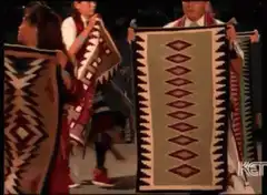 Native American dancers holding woven blankets